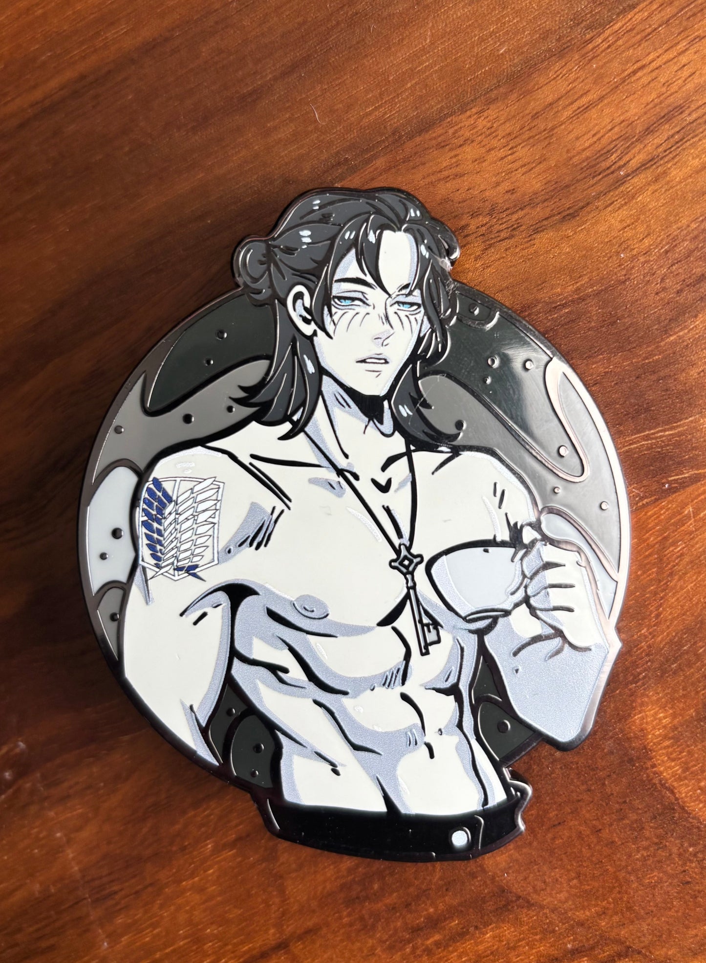 Eren Yeager enamel pin resting on an ita bag, showcasing its bold anime design and enamel detailing.